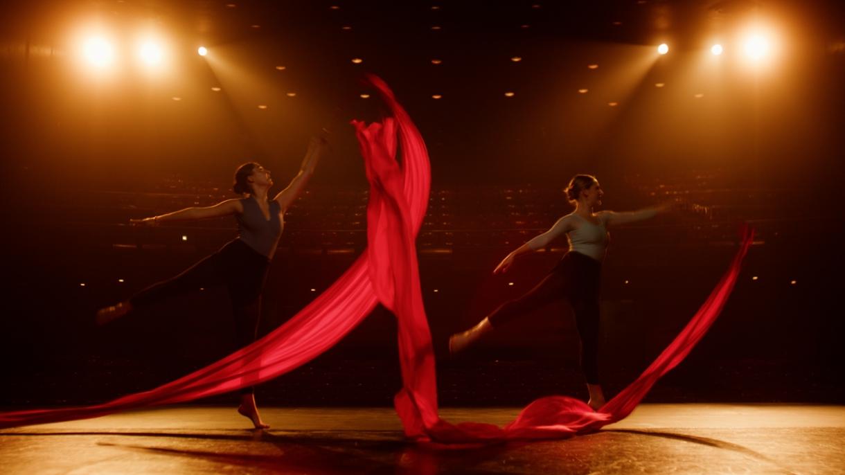 Dancers wave red ribbon on stage